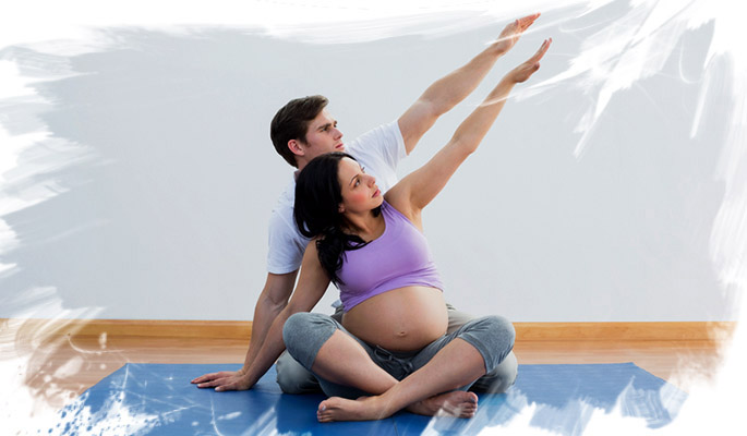 Chica embarazada y su pareja realizando ejercicios en el suelo en la clase de preparación al parto en Salud para Todos Parla